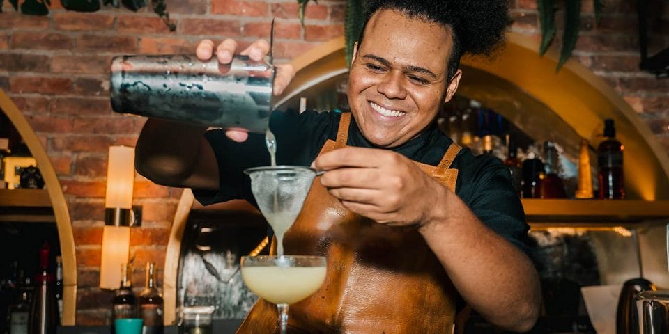 Male Bartender filtering a margarita drink