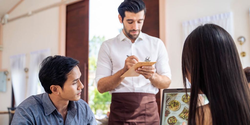 A server in a casual restaurant taking orders from clients