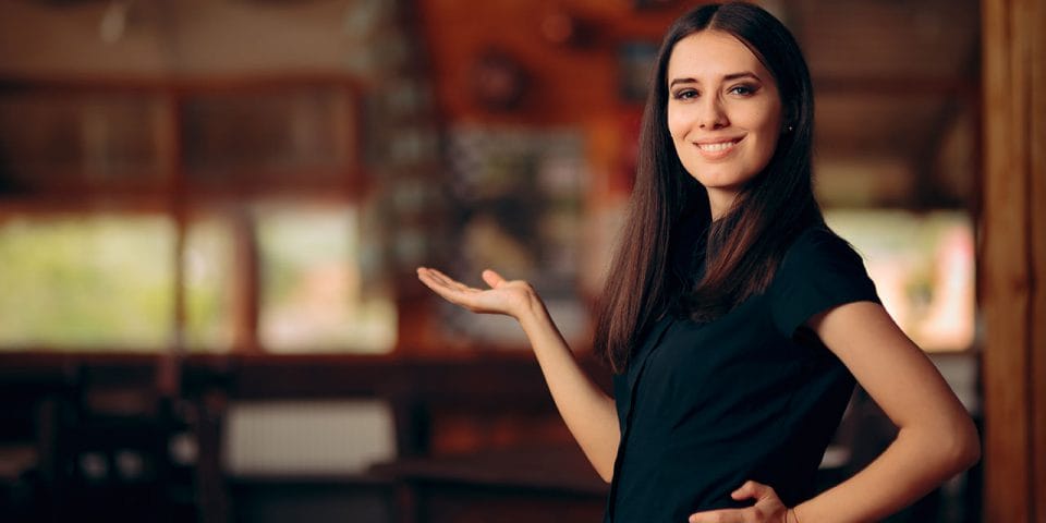 A smiling hostess welcoming restaurant guests at the entrance