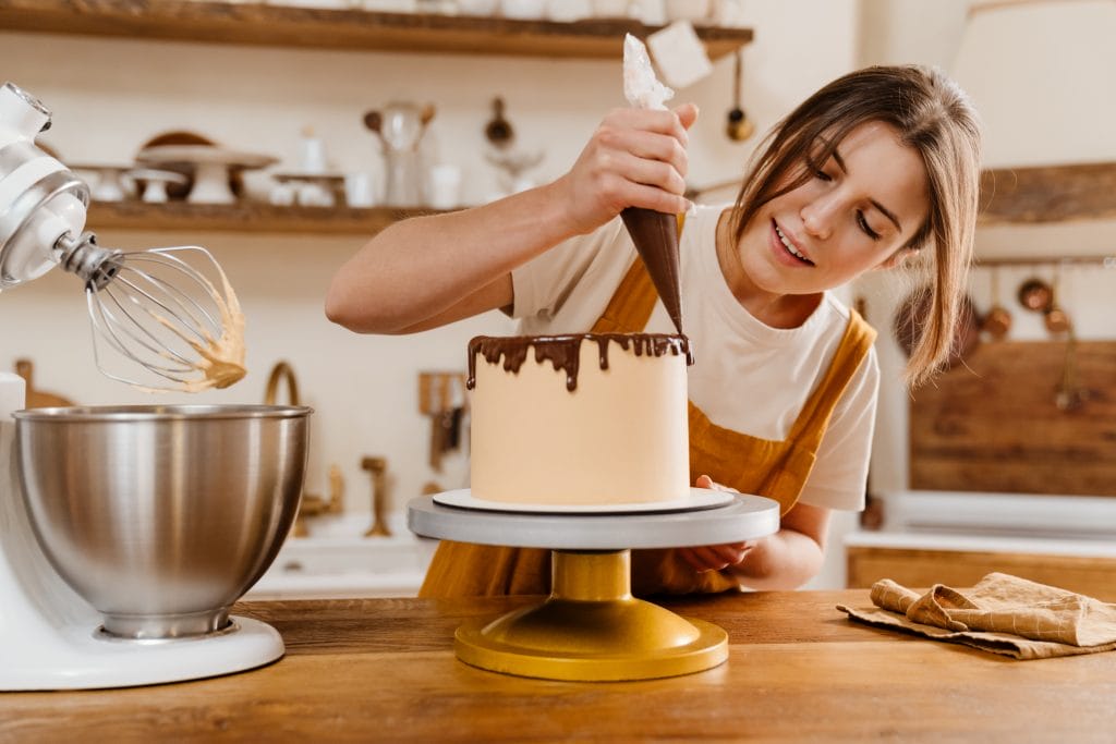 Female Pastry Chef holding a piping bag and decorating a cake