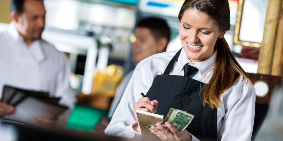 a smiling server taking payments from guests