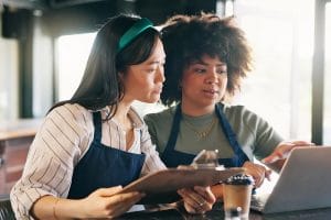 Two female Restaurant Managers budgeting using a laptop