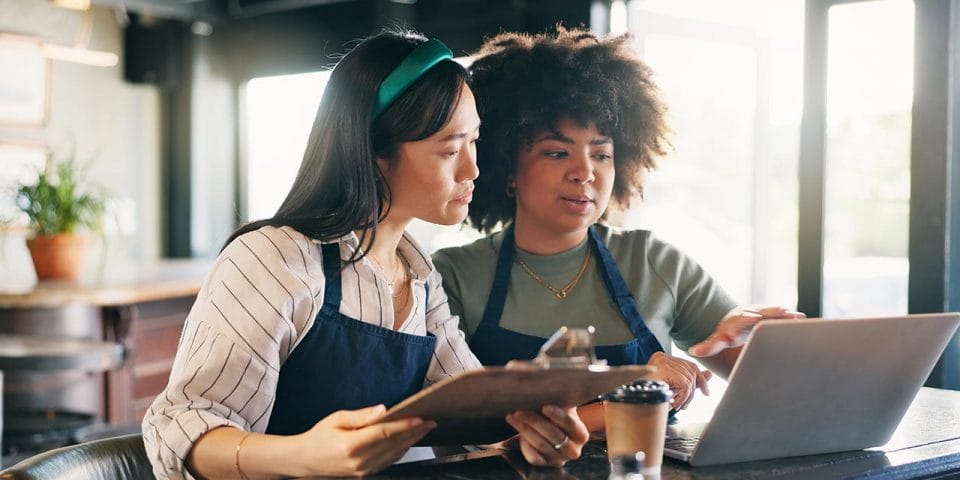 Two female Restaurant Managers budgeting using a laptop