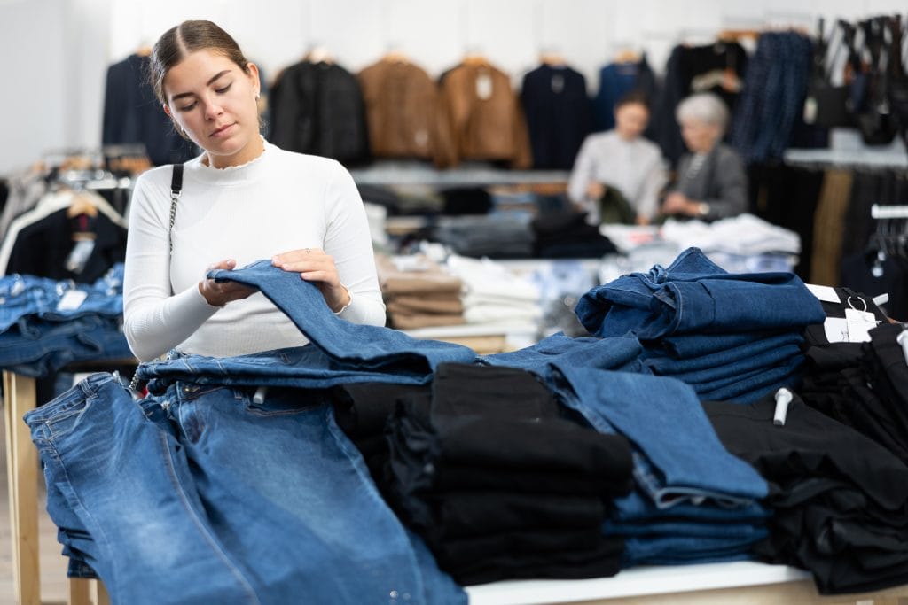 young woman checking quality of jeans at a store; can you wear jeans to a job interview?