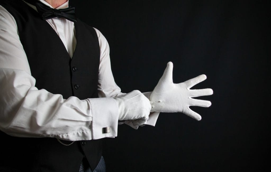 a man putting on white cotton gloves; fine dining server dress code