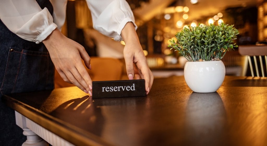 staff placing a 'reserved' sign on the restaurant table