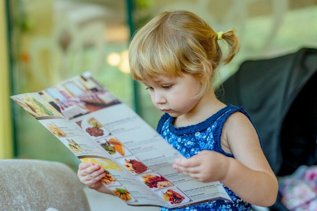 a little girl looking at a menu