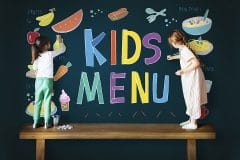 little girls drawing on a blackboard with crayons