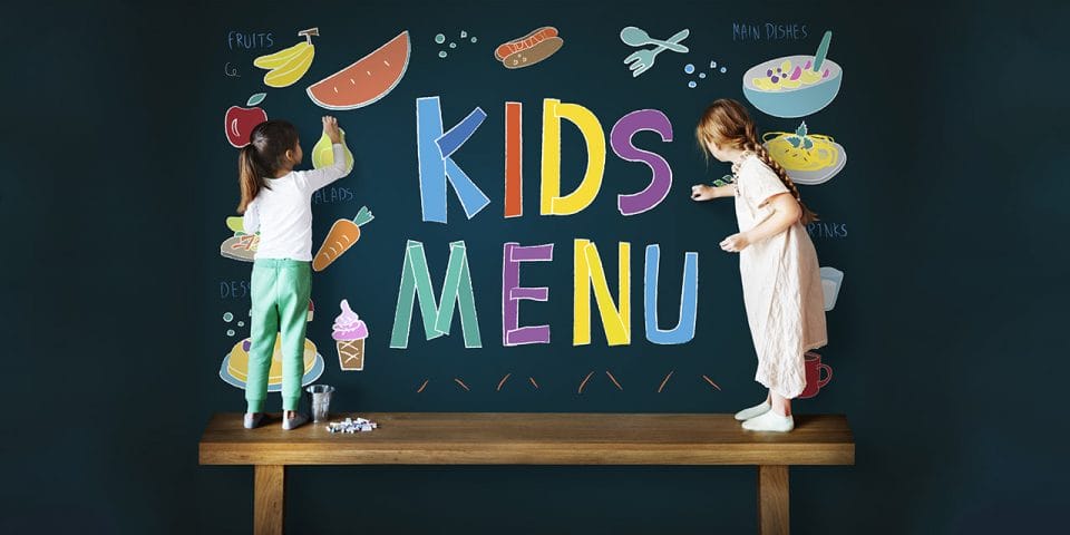 little girls drawing on a blackboard with crayons