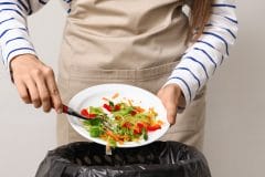 person discarding leftovers into the trash