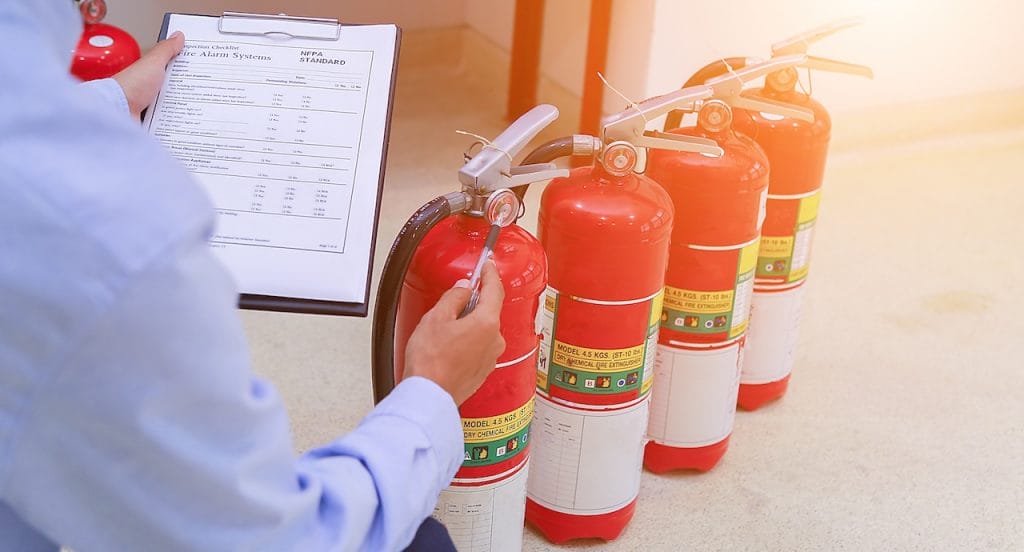 man checking fire extinguishers; restaurant kitchen fire safety measures