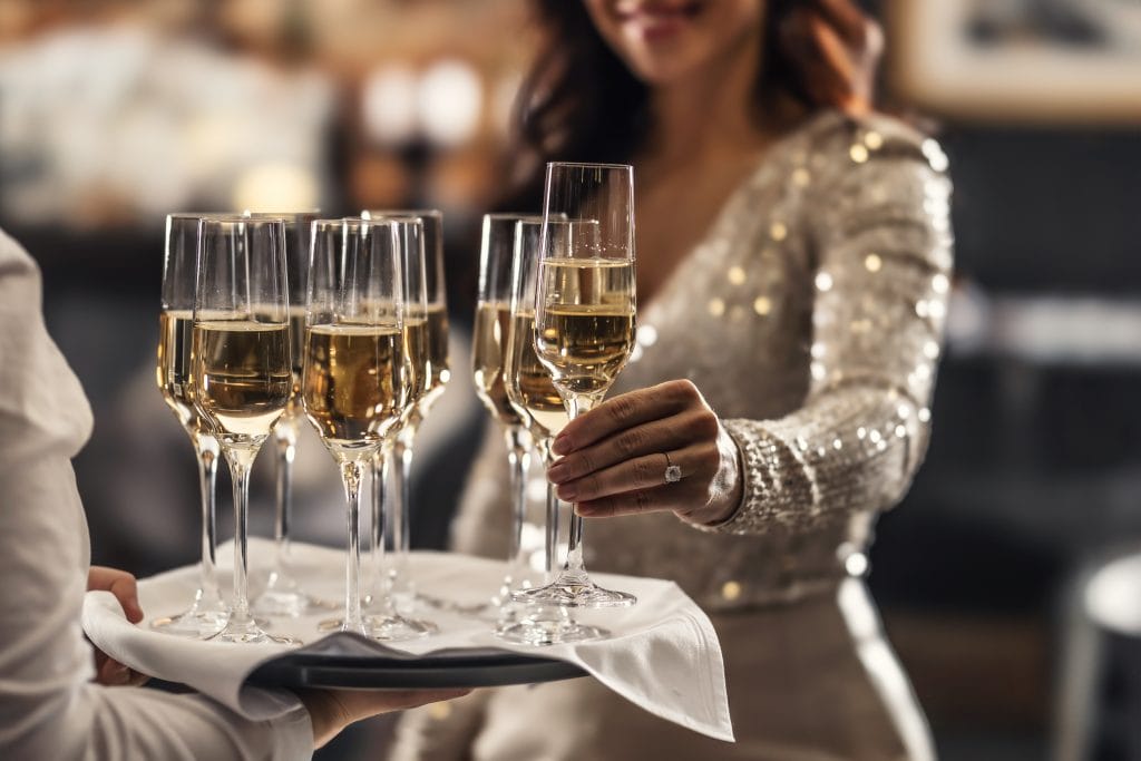 a woman grabbing a champagne glass from a platter