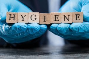 hands wearing blue gloves holding wooden cubes that say 'hygiene'