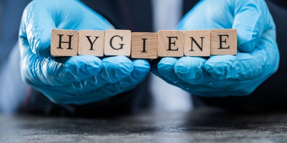 hands wearing blue gloves holding wooden cubes that say 'hygiene'