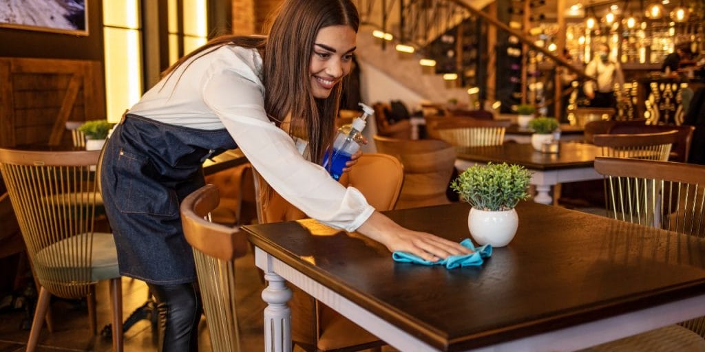 a restaurant worker wiping a table; hygiene in hospitality