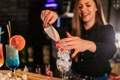 bartender putting ice into a cocktail glass