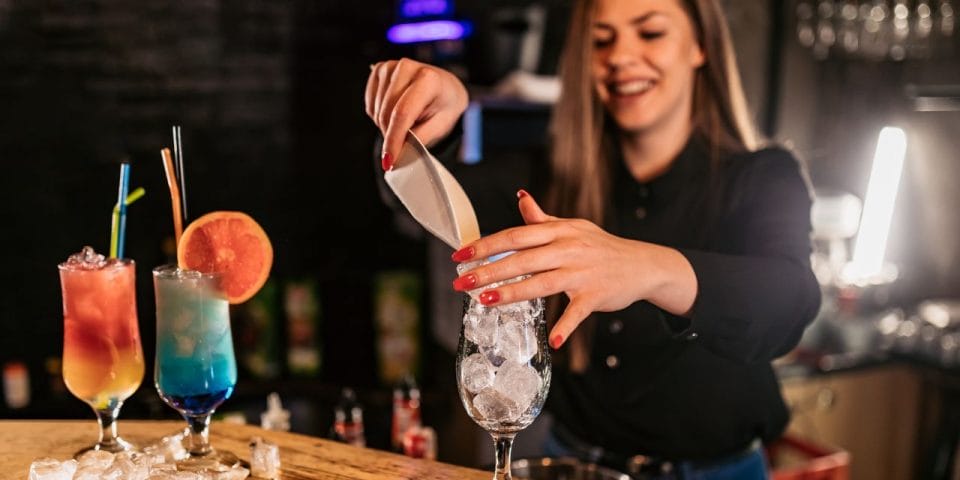 bartender putting ice into a cocktail glass