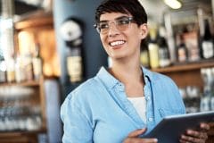 a smiling bar manager holding a tablet