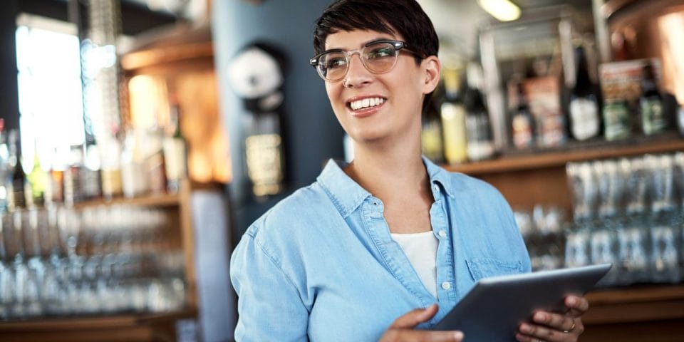 a smiling bar manager holding a tablet