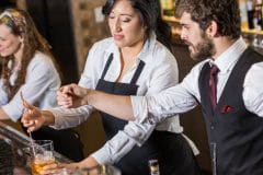 three bartenders working together behind the bar