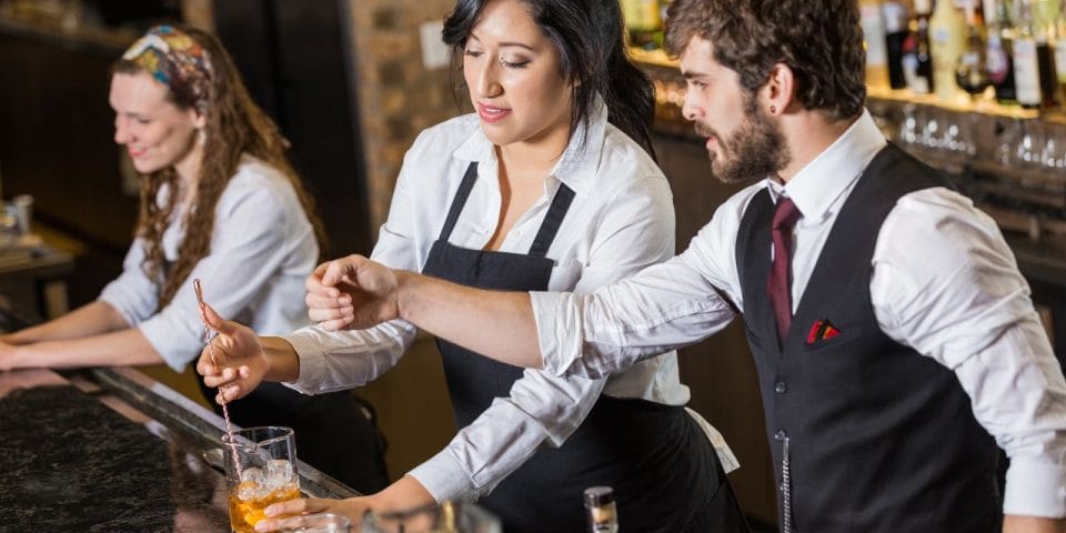 three bartenders working together behind the bar