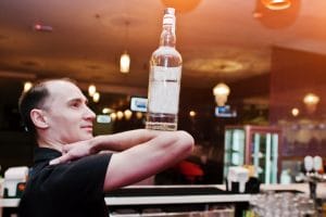 bartender balancing a bottle on his elbow