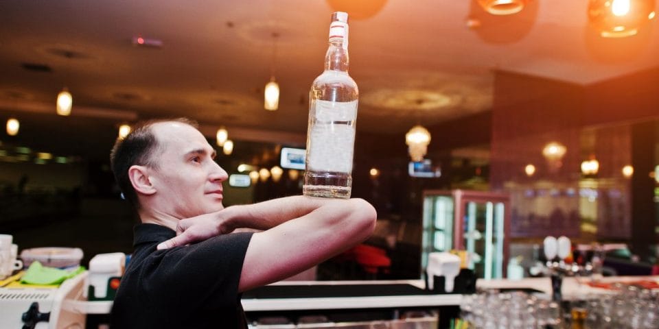 bartender balancing a bottle on his elbow