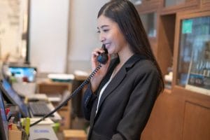 a smiling hotel front desk associate talking on the phone